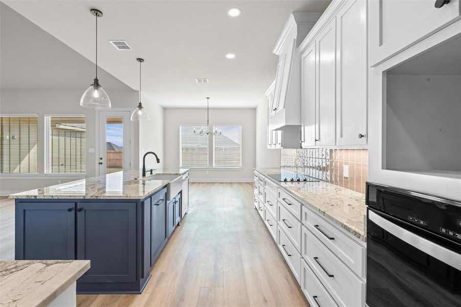Kitchen featuring white cabinetry, light stone countertops, oven, hanging light fixtures, and recessed lighting