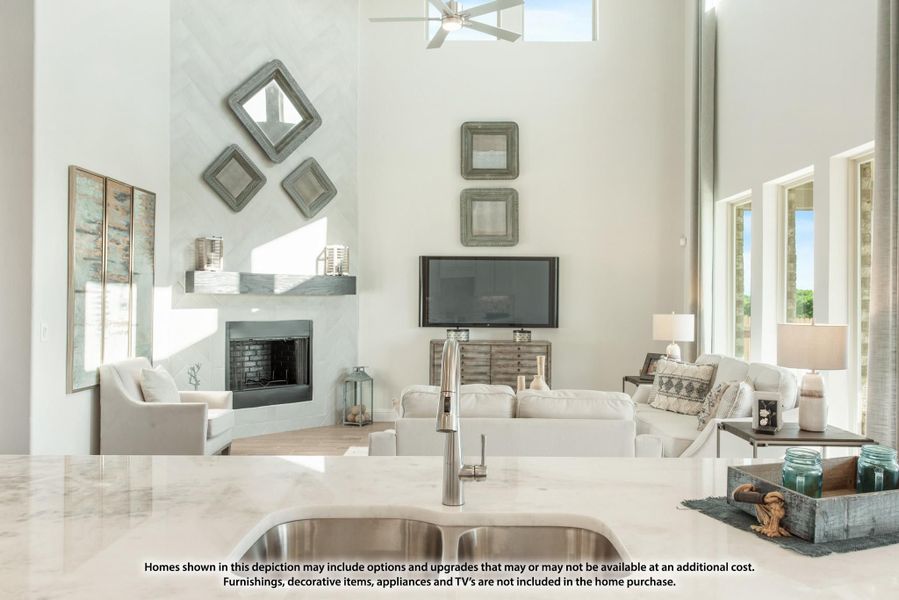 Open-concept living room with two-story ceiling, fireplace, and marble kitchen island in foreground