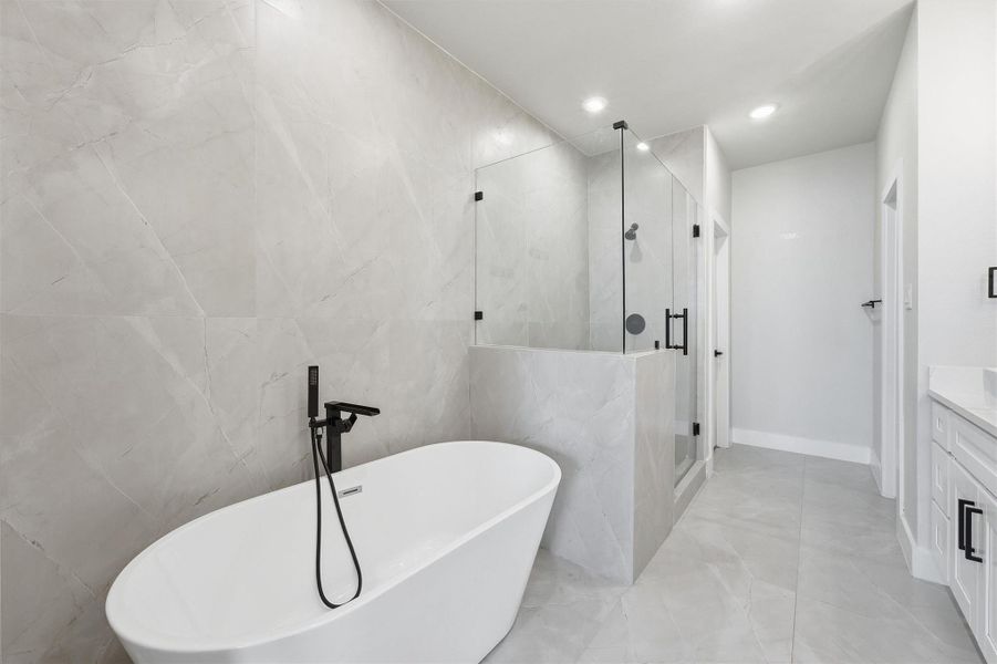 Spa-inspired primary bathroom featuring a freestanding soaking tub, oversized walk-in glass shower, and elegant full-height tile finishes for a sleek, modern retreat.