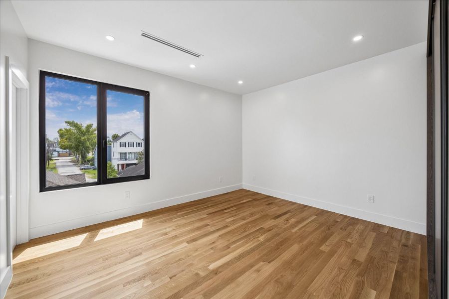 Spacious, sunlit room with hardwood floors and a large window offering neighborhood views. Spacious, sunlit room with hardwood floors and a large window offering neighborhood views.