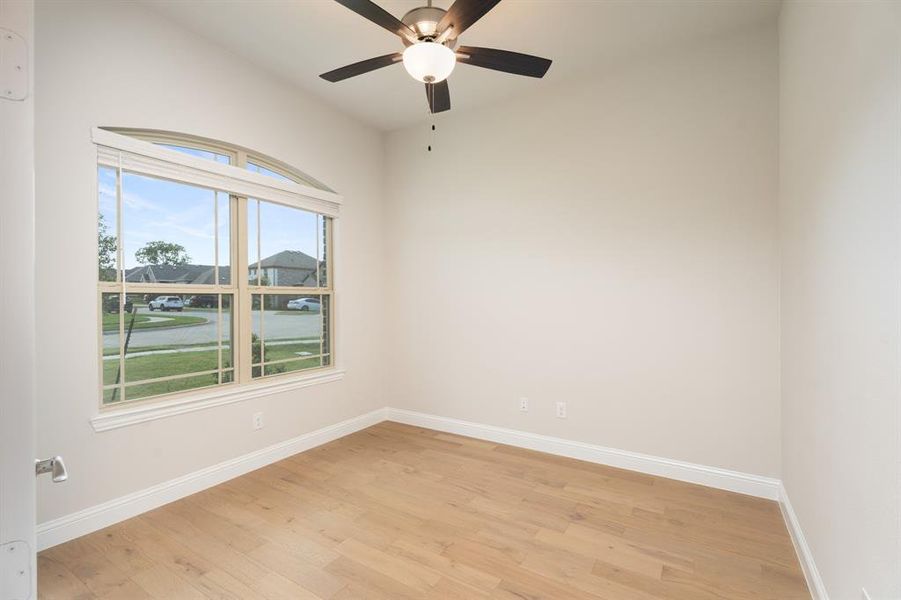 Empty room featuring light wood-style floors, a water view, and a ceiling fan