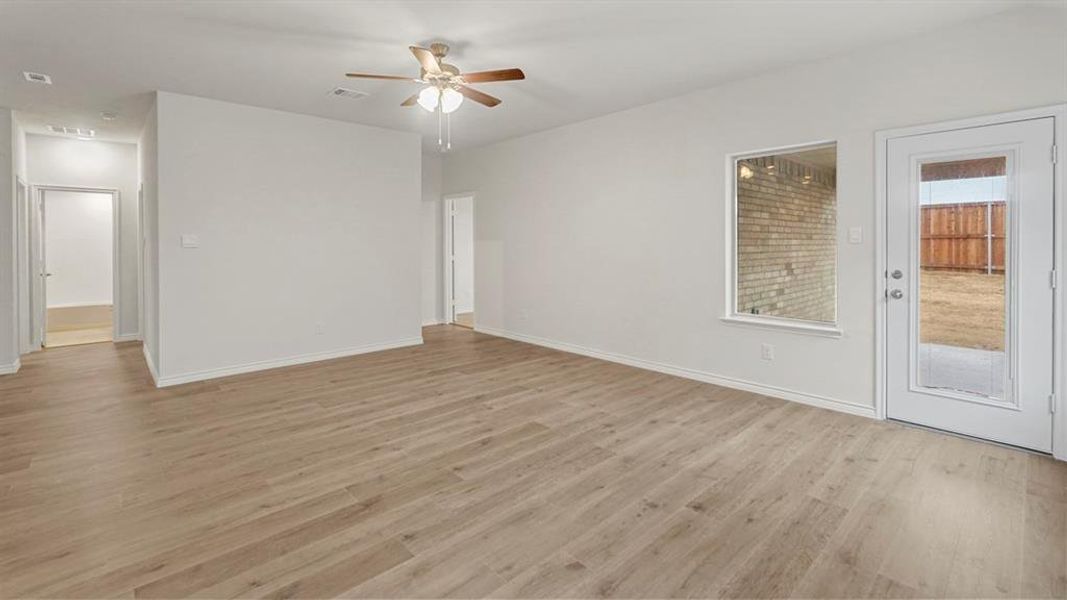 Spacious room featuring wood-finish flooring, light-toned walls, and a ceiling fan with integrated lighting
