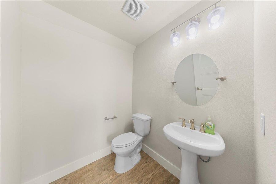 Half bath featuring wood finished floors and toilet Half bath featuring wood finished floors and toilet