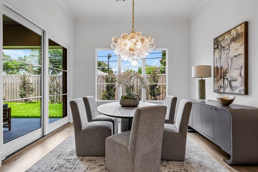 Dining area featuring ornamental molding, an inviting chandelier, and light hardwood / wood-style flooring