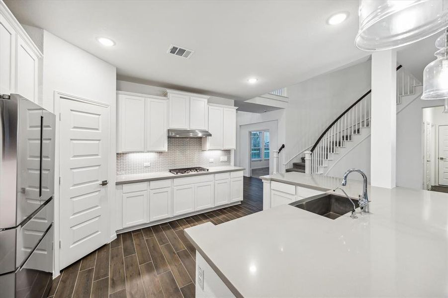 Take in another view of this spacious kitchen, showcasing the expansive countertop space that provides plenty of room for meal prep and entertaining. The gas cooktop offers precision cooking, while the large pantry ensures you have all the storage you need for ingredients and kitchen essentials. This thoughtfully designed layout enhances both functionality and style, making it a true culinary haven.