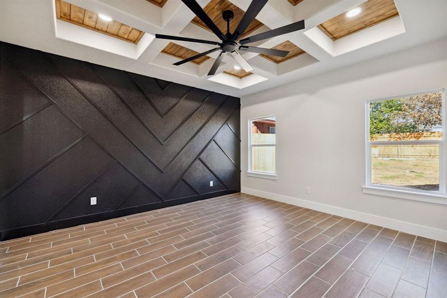 Empty room featuring ceiling fan, coffered ceiling, and beam ceiling