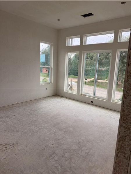 Spacious room with high ceilings featuring a prominent wall of expansive windows and transoms, offering abundant natural light