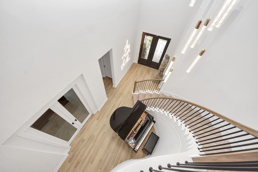 Elegant curved staircase overlooking the grand two-story foyer with modern chandelier.