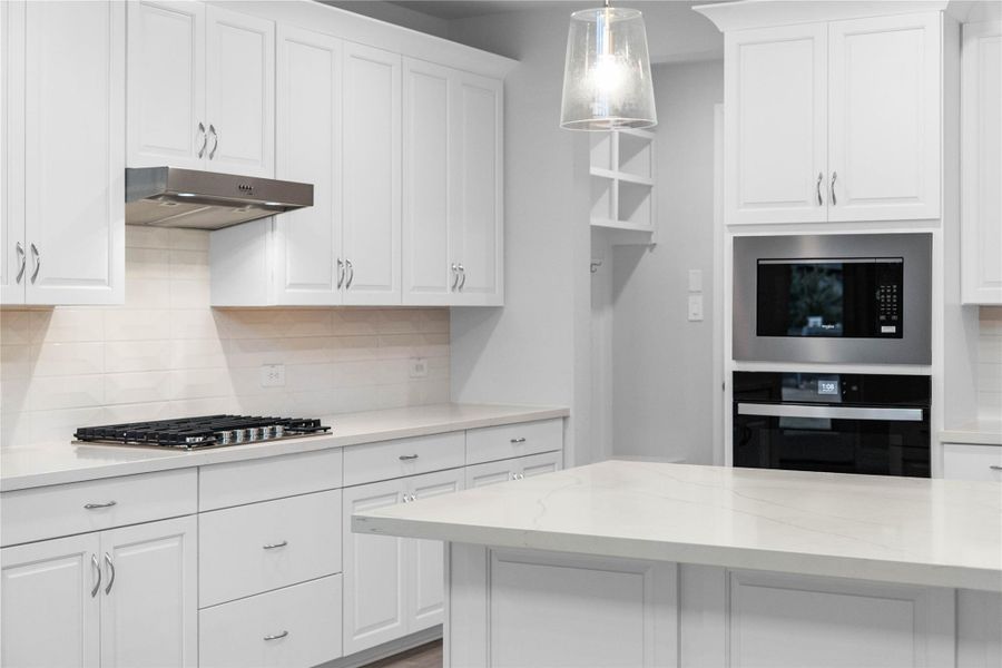 This gourmet kitchen features crisp white cabinetry, quartz countertops and Whirlpool Stainless Steel appliances.  The center island topped offers an expansive prep area and integrated stainless steel undermount sink.