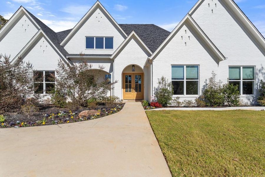 View of front of home with brick siding, a front yard, and french doors