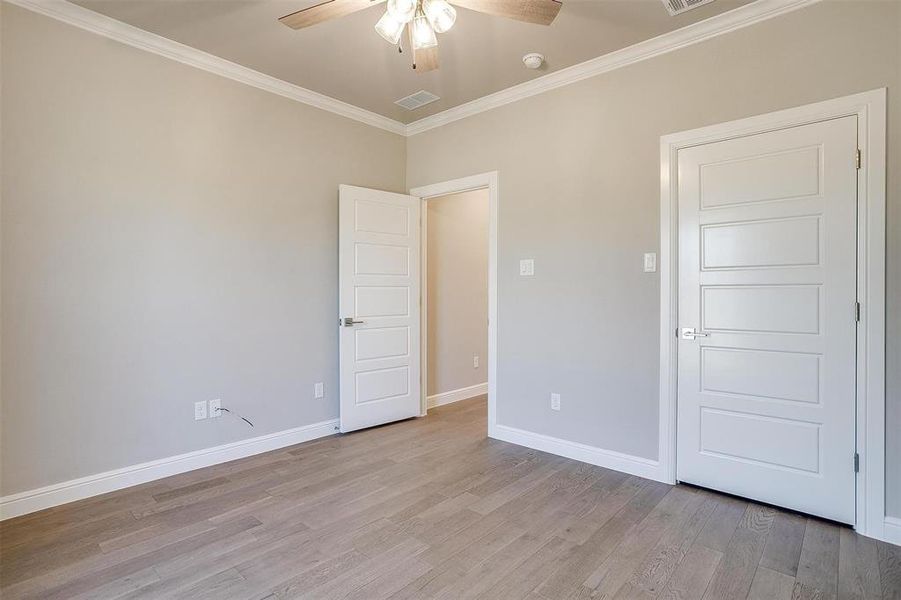 Empty room with crown molding, ceiling fan, and light wood-type flooring