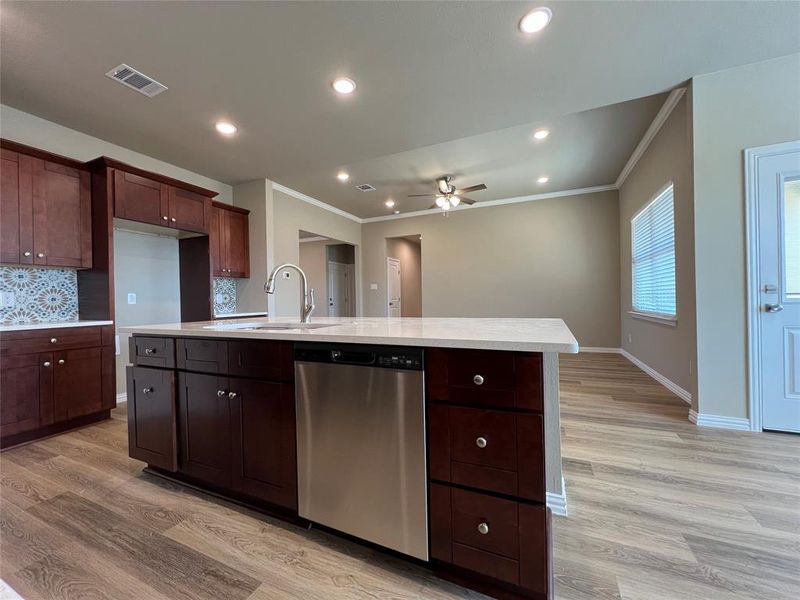 Kitchen with sink, decorative backsplash, light hardwood / wood-style flooring, ceiling fan, and stainless steel dishwasher