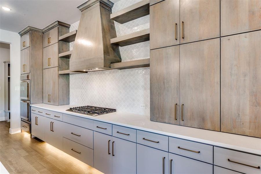 Kitchen featuring open shelves, tasteful backsplash, light wood finished floors, and premium range hood Kitchen featuring open shelves, tasteful backsplash, light wood finished floors, and premium range hood