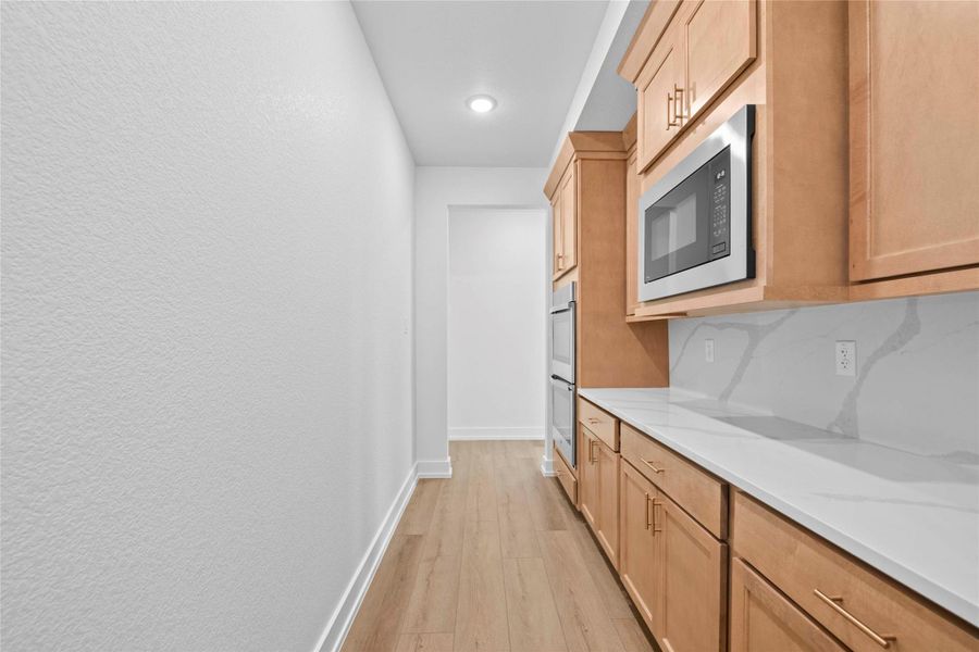 Kitchen with light wood finished floors, appliances with stainless steel finishes, tasteful backsplash, light stone countertops, and recessed lighting Kitchen with light wood finished floors, appliances with stainless steel finishes, tasteful backsplash, light stone countertops, and recessed lighting