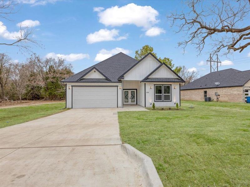 Modern inspired farmhouse featuring a shingled roof, concrete driveway, an attached garage, and a front lawn