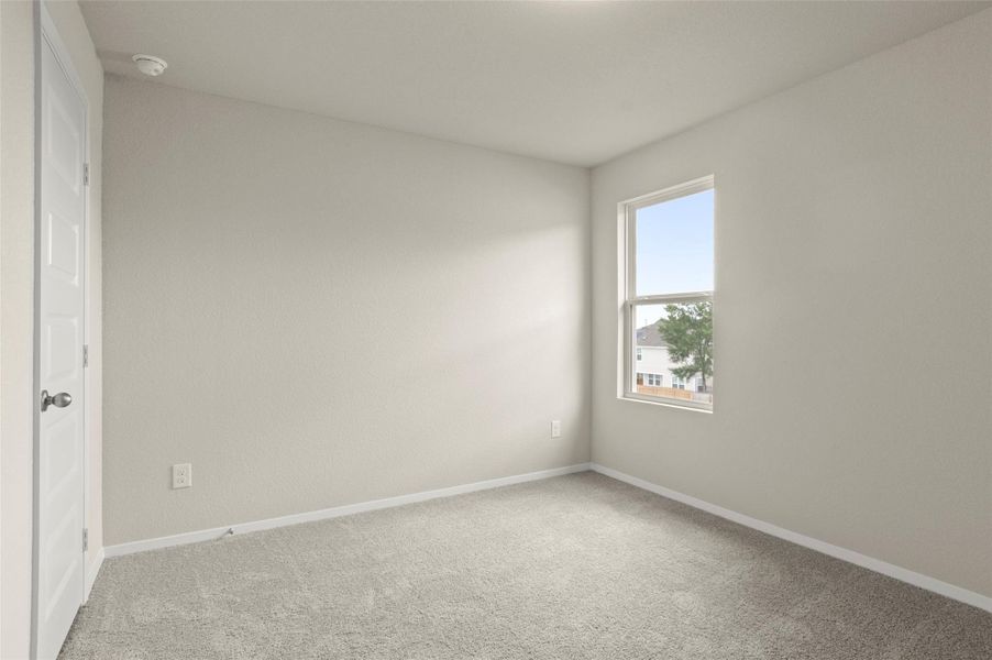 Spare room with a smoke detector and light colored carpet