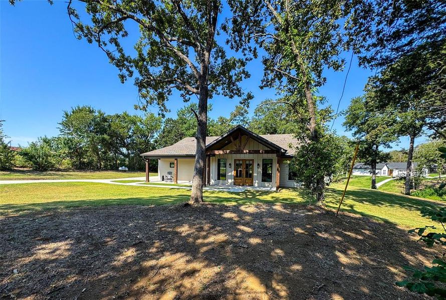 View of front facade with a porch, a front lawn, board and batten siding, and a shingled roof View of front facade with a porch, a front lawn, board and batten siding, and a shingled roof