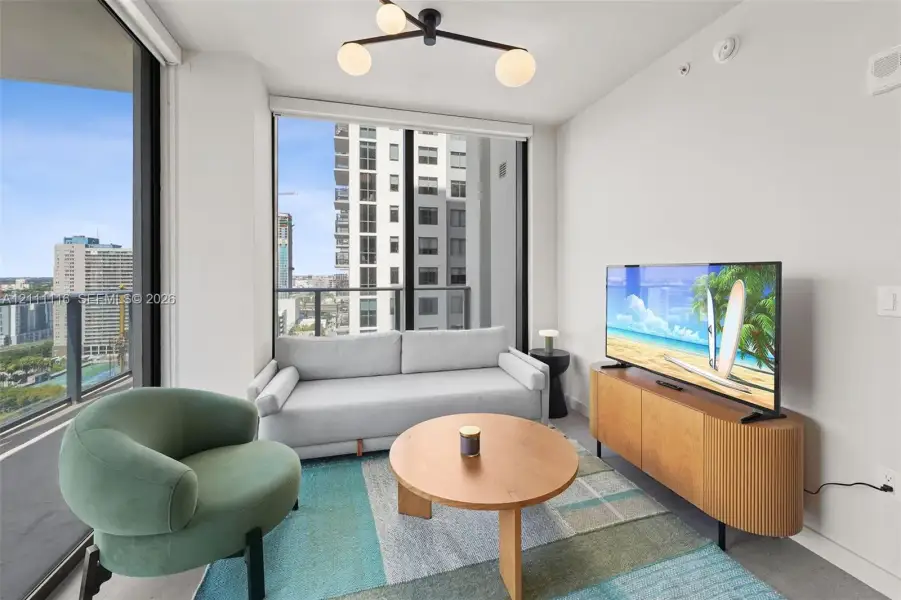 Floor-to-ceiling glass windows, matte black frame balcony railing, modern three-arm globe chandelier, and neutral wall finish