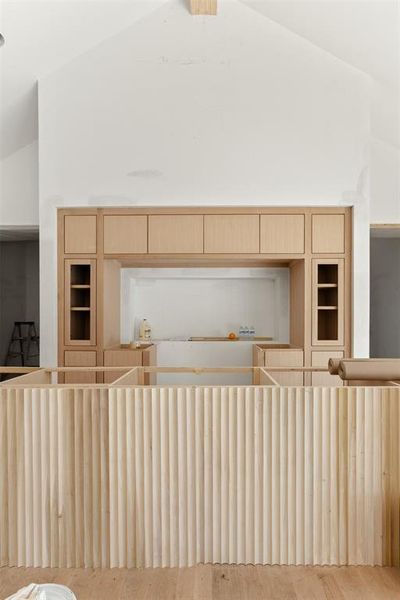 Kitchen with light brown cabinets, built in features, high vaulted ceiling, and hardwood / wood-style floors