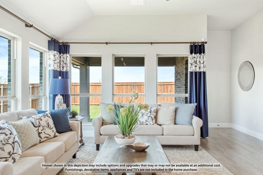 Living room with vaulted ceiling, large windows, hardwood floors, and two beige sofas with blue accent pillows