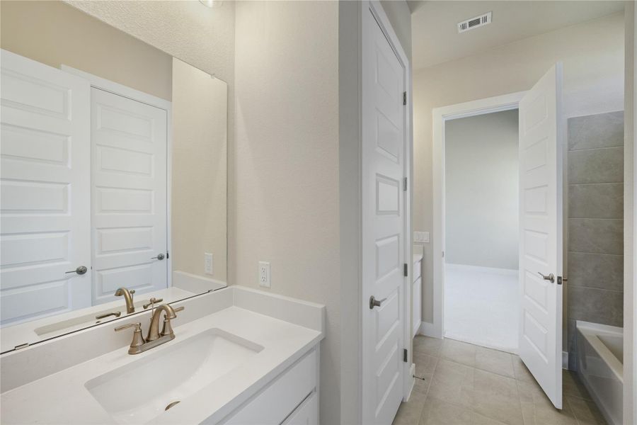 Bathroom featuring vanity, light tile patterned flooring, and a bathtub