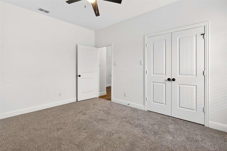 Unfurnished bedroom featuring carpet flooring, a closet, and a ceiling fan