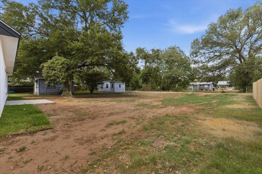 Mature trees shade a spacious outdoor area bordered by a wood privacy fence. Mature trees shade a spacious outdoor area bordered by a wood privacy fence.