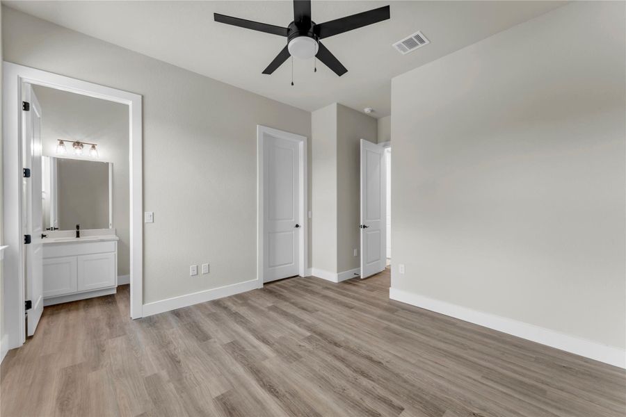 Unfurnished bedroom with light wood finished floors, ceiling fan, and ensuite bath