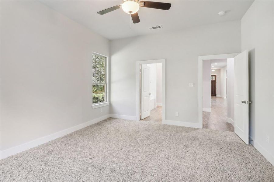 Unfurnished bedroom featuring ensuite bath, ceiling fan, and light colored carpet