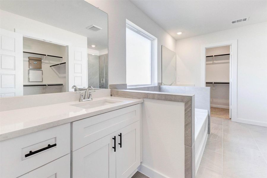 The ensuite bathroom stuns with quartz-topped dual vanities, a soaking tub with tile surround, and ample natural light. With direct access to a spacious walk-in closet, this space combines spa-inspired luxury with practical functionality. The ensuite bathroom stuns with quartz-topped dual vanities, a soaking tub with tile surround, and ample natural light. With direct access to a spacious walk-in closet, this space combines spa-inspired luxury with practical functionality.