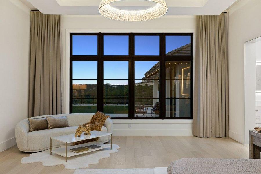 Floor-to-ceiling windows flood this elegant sitting area with natural light and offer expansive outdoor views.