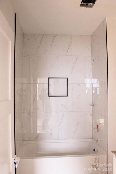 Updated secondary bathroom with modern tile and a framed niche.