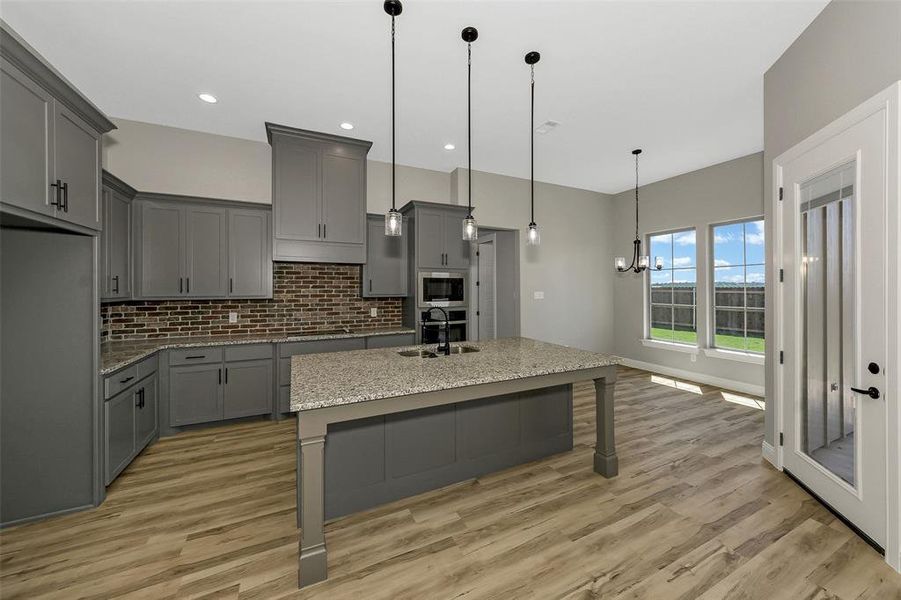 Kitchen with gray cabinetry, light wood-style floors, tasteful backsplash, and recessed lighting
