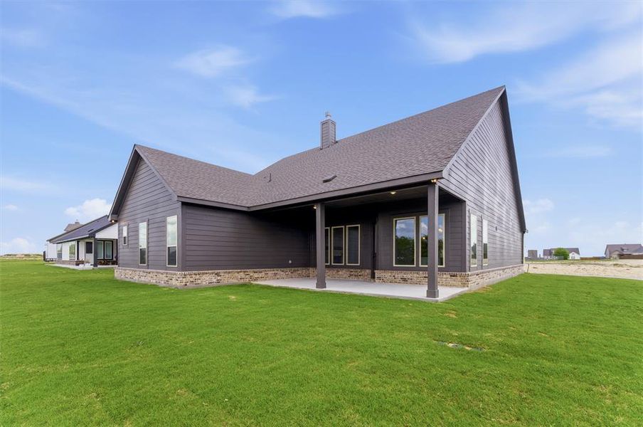 Back of property featuring a shingled roof, a patio, a lawn, and a chimney Back of property featuring a shingled roof, a patio, a lawn, and a chimney