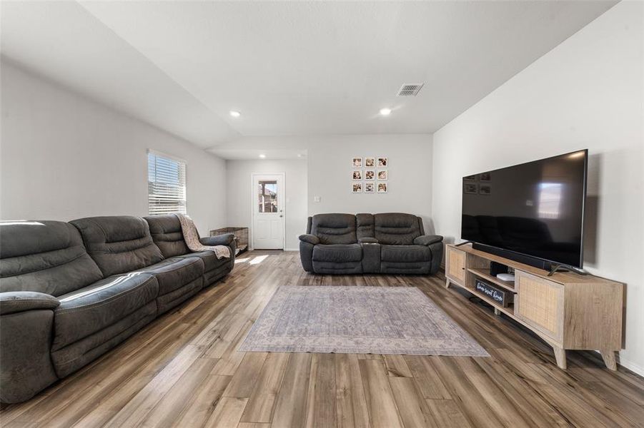 Living room featuring wood finished floors, recessed lighting, and vaulted ceiling