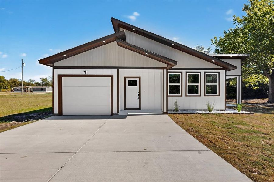 View of front facade featuring a front lawn, driveway, and an attached garage View of front facade featuring a front lawn, driveway, and an attached garage