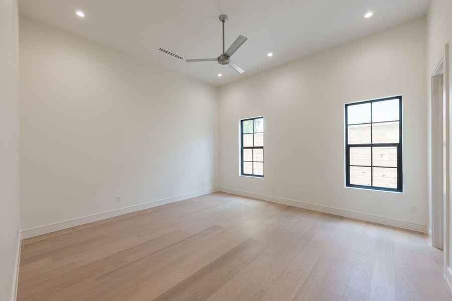 Few design elements change the way a room feels quite like scale. Here, soaring ceilings and oversized steel-framed windows draw in natural light throughout the day, creating a space that feels open, airy, and effortlessly serene. Wide-plank engineered hardwood floors add warmth underfoot, grounding the room in a palette inspired by natural materials.