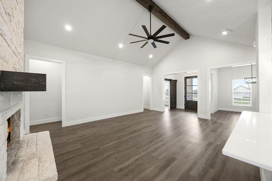 Spacious living area featuring high vaulted ceilings with exposed wood beam, recessed lighting, and wood-finish flooring