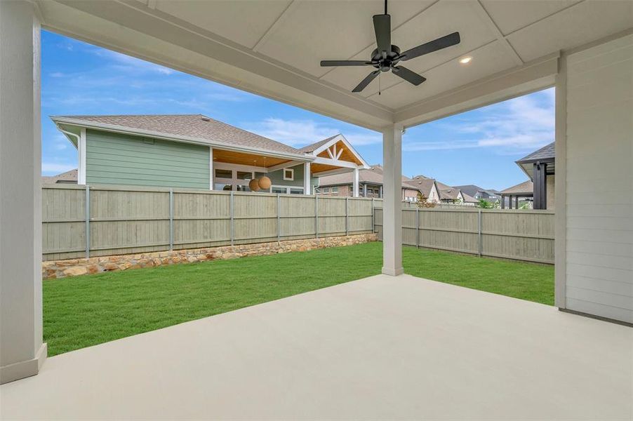 The property features a covered patio with a ceiling fan and recessed lighting, overlooking a well-maintained lawn