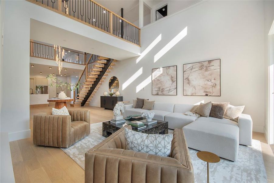 Living area featuring wood finished floors, stairs, and a towering ceiling Living area featuring wood finished floors, stairs, and a towering ceiling