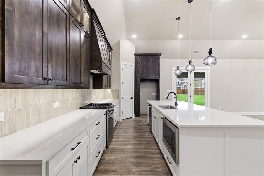 Kitchen featuring dark wood-finish upper cabinetry, white lower cabinetry, and an expansive white countertop island Kitchen featuring dark wood-finish upper cabinetry, white lower cabinetry, and an expansive white countertop island