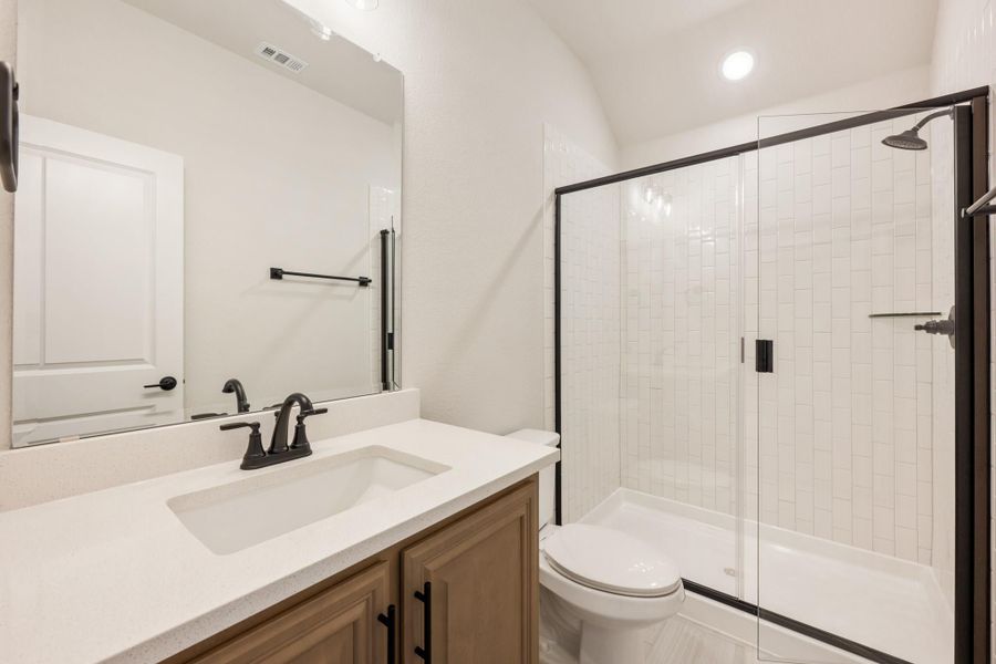 Bathroom with single vanity, white quartz countertop, glass shower enclosure, and black fixtures Bathroom with single vanity, white quartz countertop, glass shower enclosure, and black fixtures