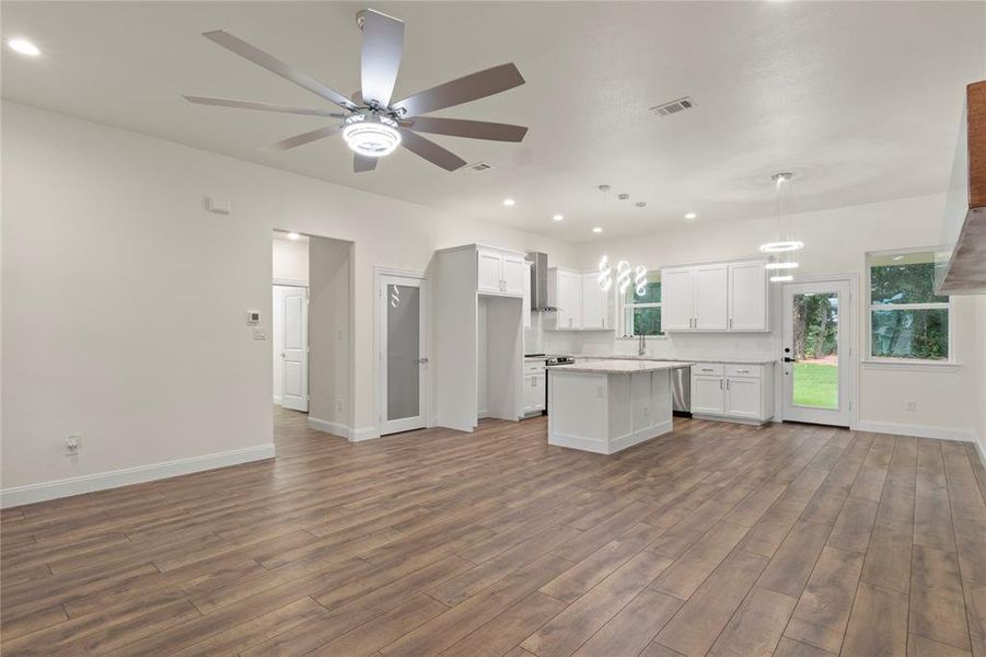 Spacious open-concept living area featuring wood-finish flooring, recessed lighting, and a modern ceiling fan Spacious open-concept living area featuring wood-finish flooring, recessed lighting, and a modern ceiling fan