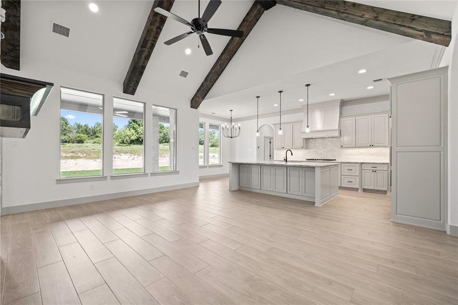 Unfurnished living room featuring ceiling fan, recessed lighting, beamed ceiling, light wood-style floors, and high vaulted ceiling Unfurnished living room featuring ceiling fan, recessed lighting, beamed ceiling, light wood-style floors, and high vaulted ceiling