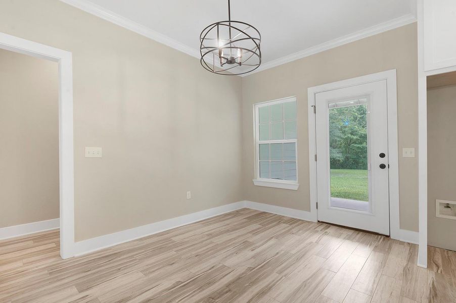 This is a bright, neutral-colored room featuring wood-style flooring and a modern light fixture. It has a window and a glass door leading to a grassy backyard, offering natural light and easy outdoor access. This is a bright, neutral-colored room featuring wood-style flooring and a modern light fixture. It has a window and a glass door leading to a grassy backyard, offering natural light and easy outdoor access.