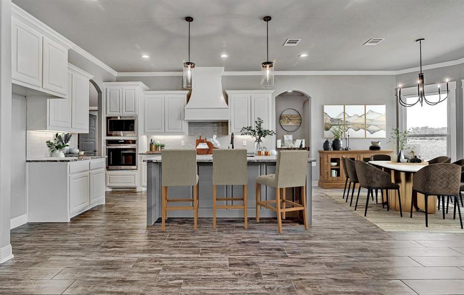 Kitchen featuring appliances with stainless steel finishes, backsplash, white cabinetry, and a kitchen island with sink