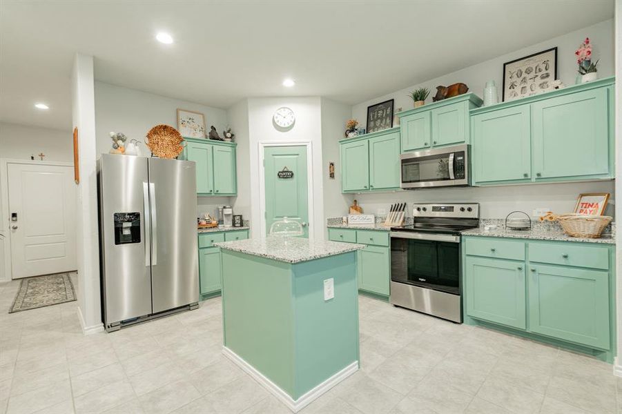 Kitchen with green cabinetry, appliances with stainless steel finishes, recessed lighting, and a center island