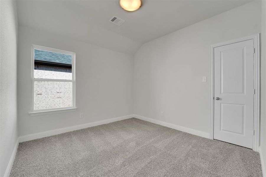 Carpeted spare room with baseboards, visible vents, and vaulted ceiling Carpeted spare room with baseboards, visible vents, and vaulted ceiling