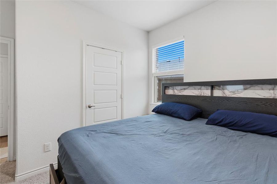 Bedroom featuring white walls, carpet flooring, a multi-panel interior door, and a window with blinds
