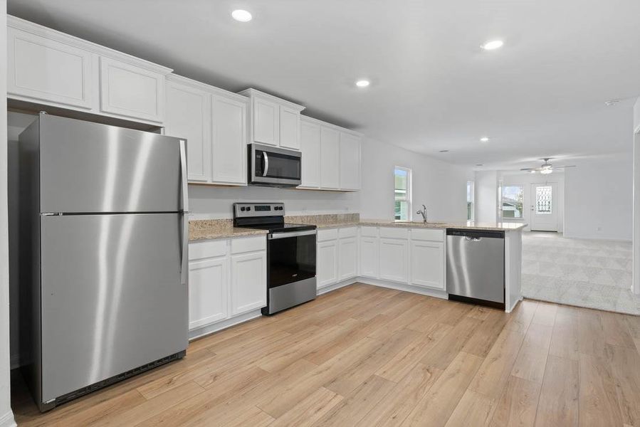 Chef ready kitchen which includes a suite of energy-efficient Whirlpool appliances - including refrigerator with ice maker, granite countertops, designer white cabinetry and luxury vinyl plank flooring